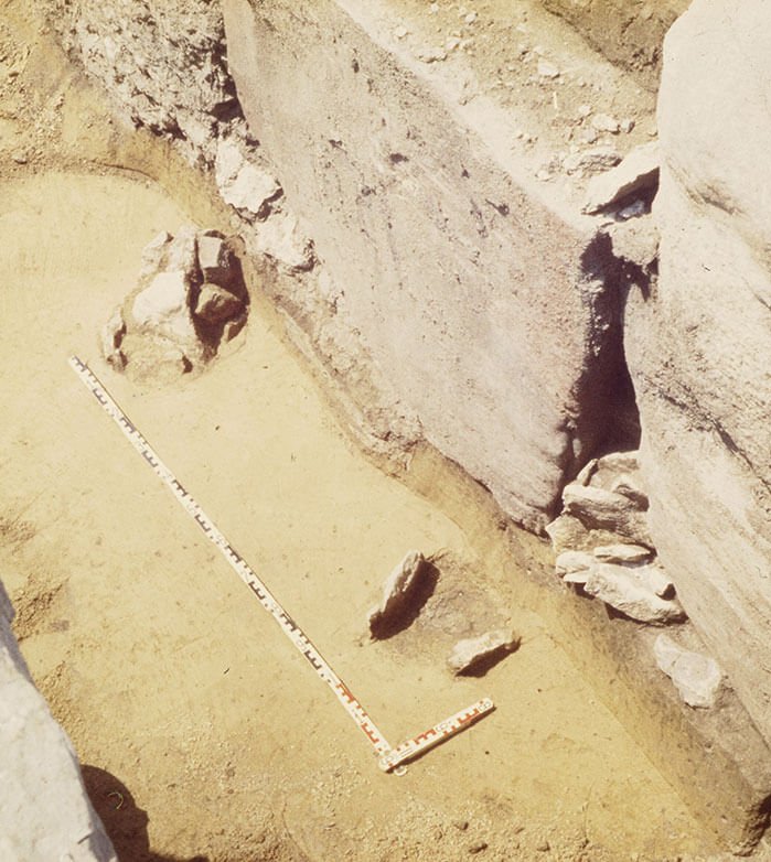 Lower part of the red sandstone slab with broken edge. The two postholes are visible in front of it. View from the south-east. Photo: © LDA.